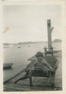 Image of Eskimo [Inuk] boy in wheelbarrow on dock
